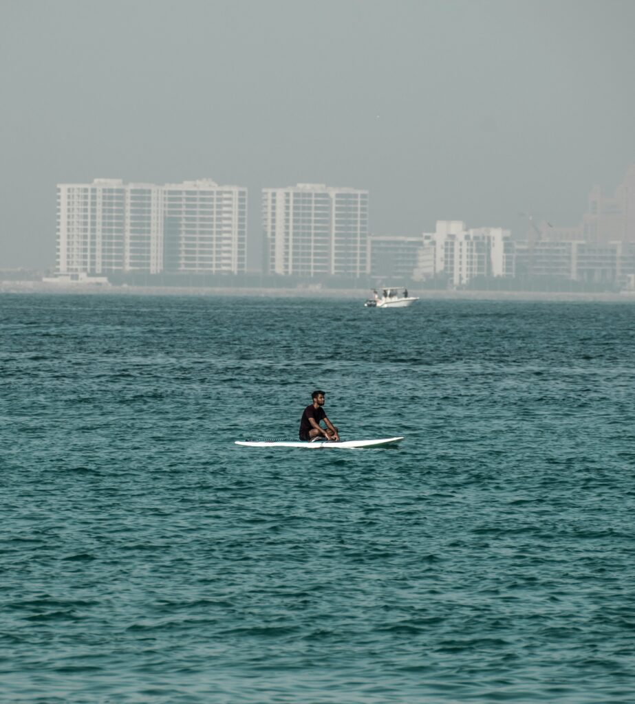 A Man Riding on Surfboard in Sea Sandboarding Dubai 