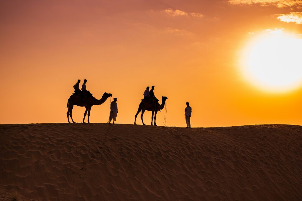 nikhil-shetty-Z7QeMzyWu40-unsplash A group of Tourist riding on Camel in Sunrise Desert Safari Dubai