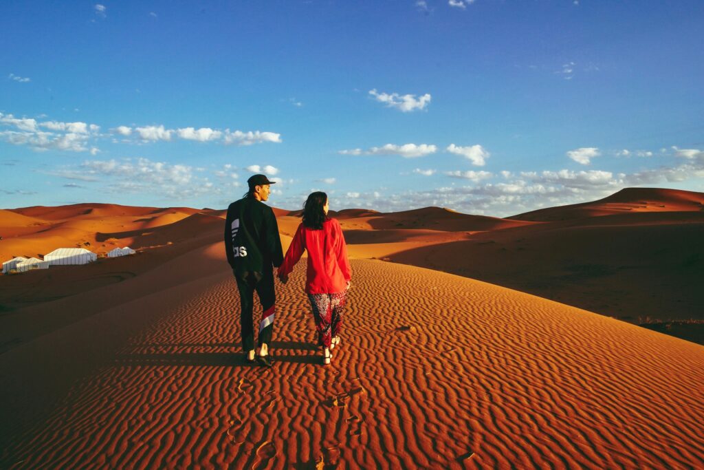 A Couple Holding Their Hands Walking on Sand Stay in Desert Dubai