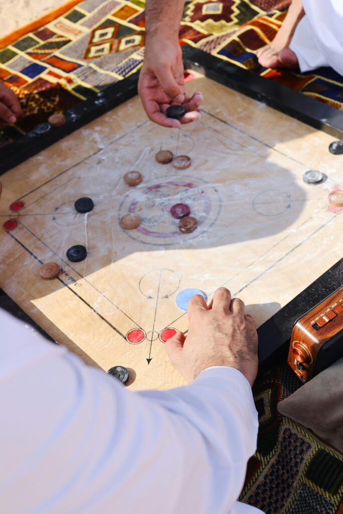 A Group Of People Playing A Caraam board on Sand Dune Abu Dhabi