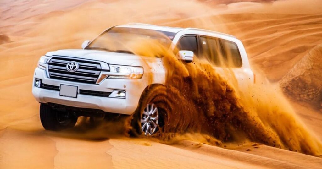 White SUV on golden desert dunes in Dubai